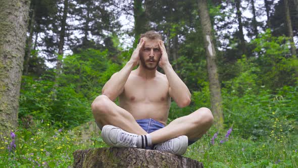 Man rubbing his head in the forest.