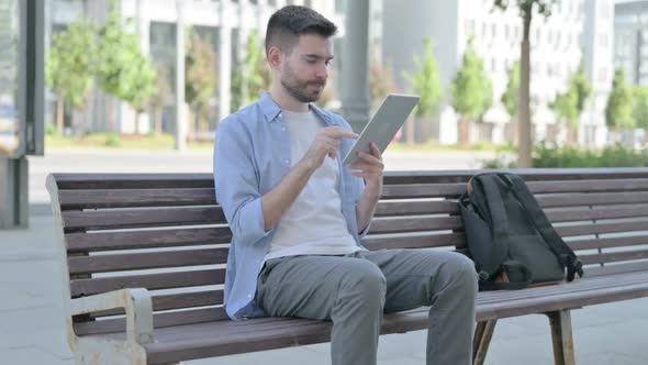 Young Man Using Tablet While Sitting on Bench