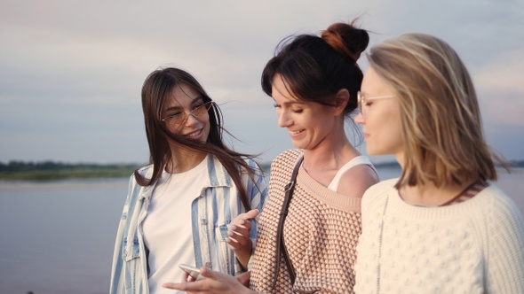 Women using a smart phone outdoors looking very happy.