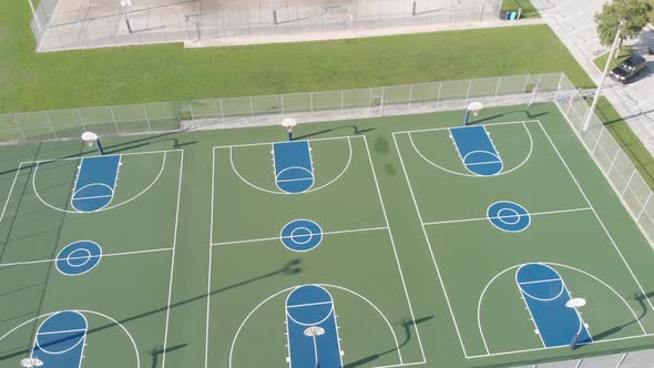 Aerial drone view of perfectly painted basketball courts.  Smooth orbit to a view of an adjacent lak