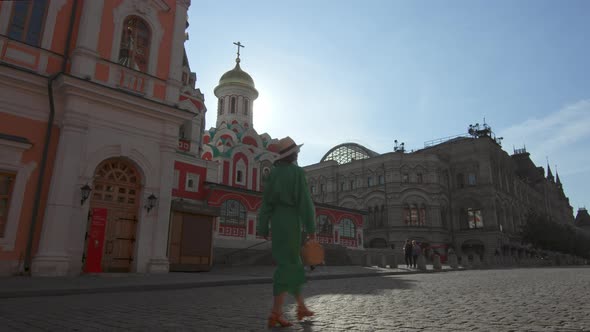 A girl in a green dress walking by the cathedral on Red Square