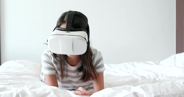 Woman wearing virtual reality device on bed