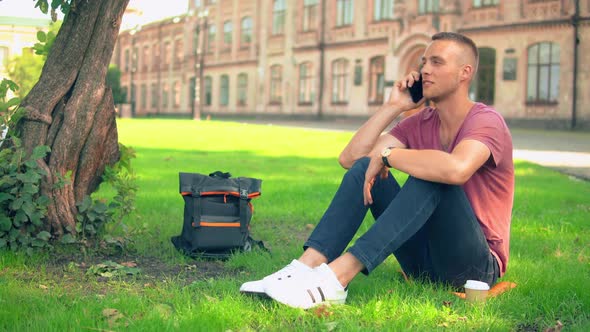 Guy Sits Near the Tree Has Phone Conversation