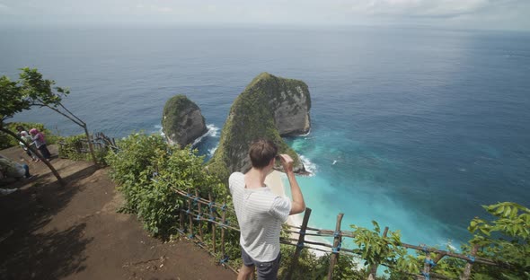 Male Tourist Putting on Sunglasses and Observing Beautiful Tropical TRex Bay Peninsula at Kelingking