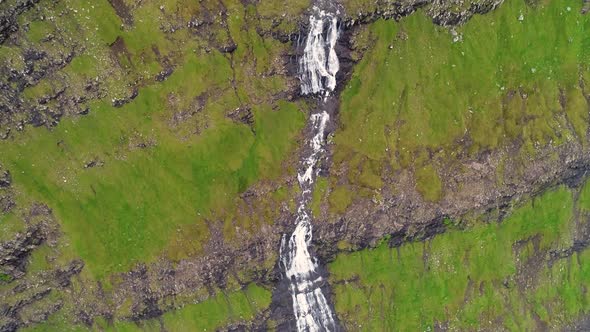 Aerial view of breathtaking waterfall crossing rock mountain, Faroe Island.