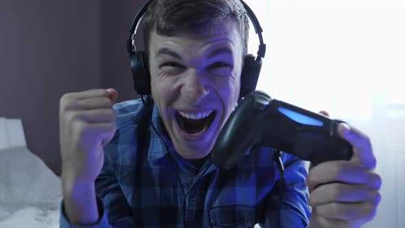 Portrait of excited young man playing video games with joystick, having fun at home