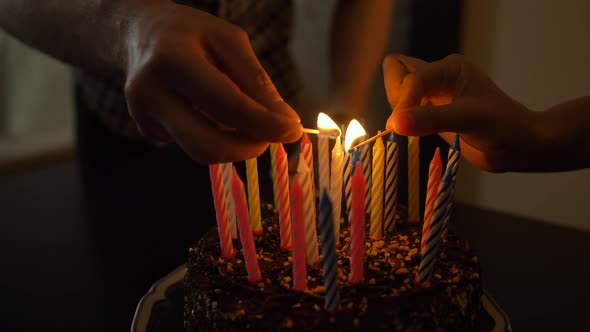 Woman and Man Lights Candles on Tasty Birthday Cake. Prepearing for Party.