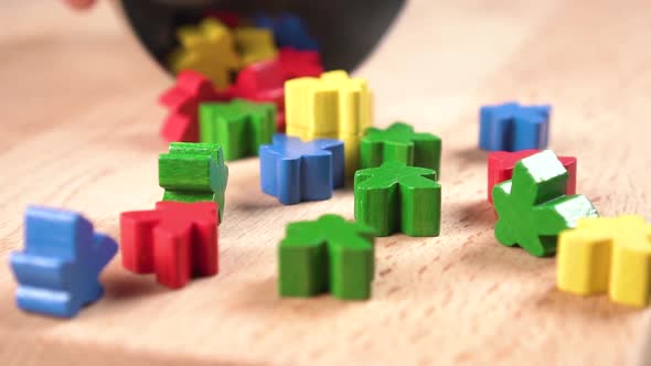 Multicolored figurines fall in slow motion on a wooden surface close-up