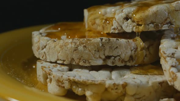 Round Rye Grain Slice with Honey Poured on Top Rotate on a Yellow Clay Plate