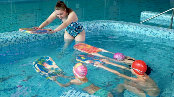 Group of Boys and Girls Train and Learn to Swim in the Pool with an Instructor