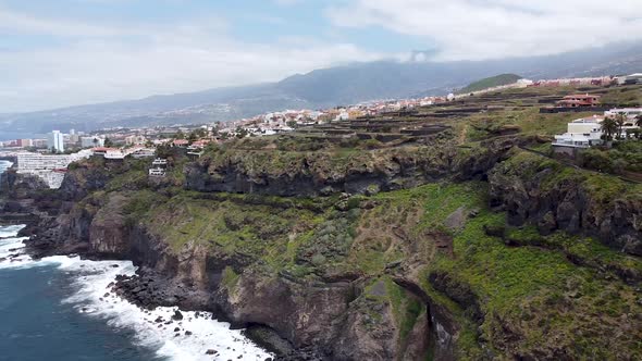 Drone aerial view of an epic steep coastline with villages and houses next to the drop in northern T