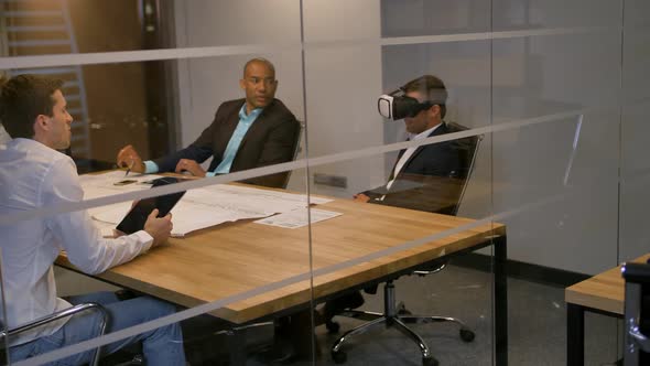 Business Team Sitting at a Table, Man with Virtual Reality Goggles. People Testing Vr Headset in