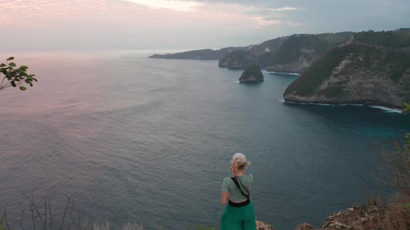 Female Tourist Standing By the Edge of the Cliff To Admire Vast Ocean Waters