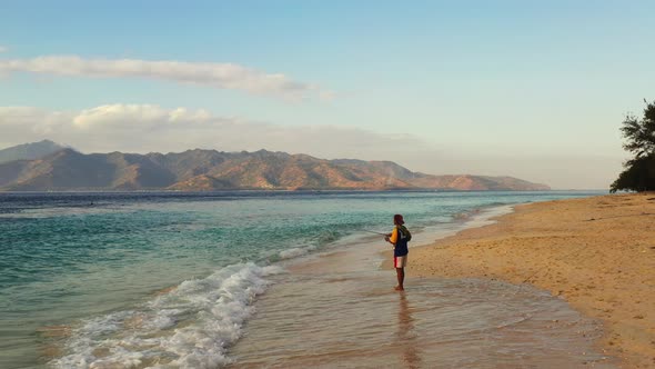 Fishing for cute teenager relaxes and has fun at beach on paradise white sand and blue background 4K