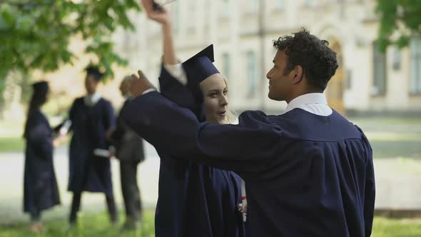 Young people in academic regalia talking, joking and having fun together