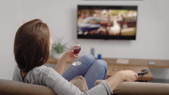 Young Woman with Glass of Drink Near TV in Room