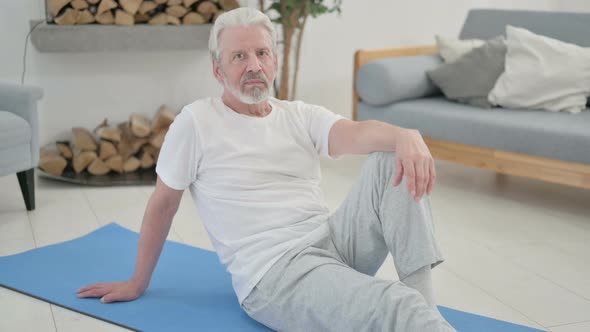 Old Woman Looking at the Camera While Sitting on Yoga Mat