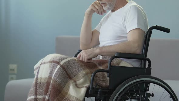 Injured man sitting in wheelchair, starting to push it hands striving to recover