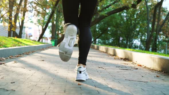 Female feet in sneakers running in park