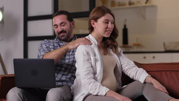 Caring Husband Doing Massage To Pregnant Woman