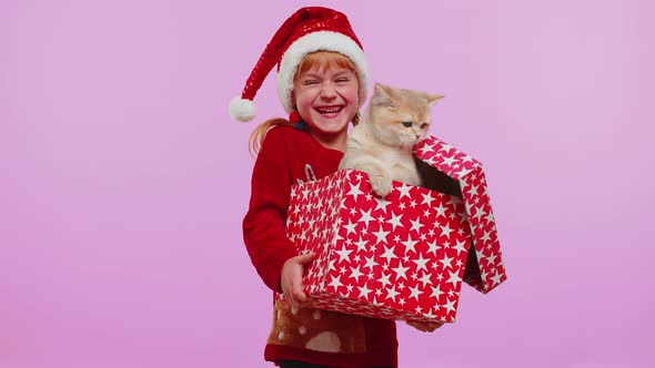 Girl in Christmas Red Sweater Hat Smiling Unwrapping Gift Opening Box with Pet Cat Great Surprise