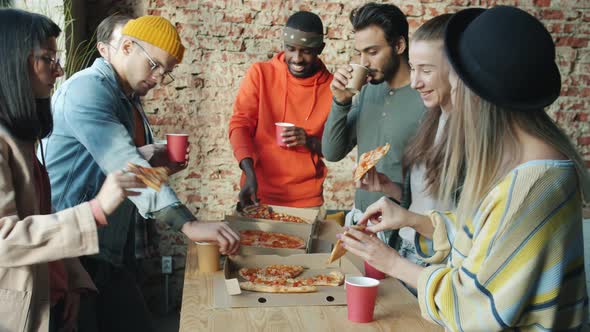 Multiethnic Group of Businesspeople Eating Pizza Together in Modern Loft Style Office