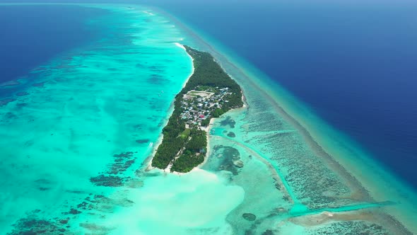 Daytime fly over island view of a sandy white paradise beach and aqua blue water background