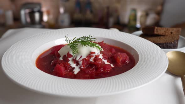 Plate of red beetroot soup borsch rotates on table. Traditional Ukraine food