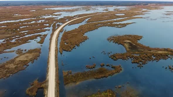 Drone approaches the road through the lake with shallows (North Shoal Lake, Manitoba, Canada)