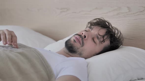 Tired Young Casual Man with Headache Lying in Bed