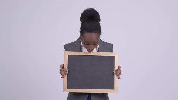 Young African Businesswoman Holding Blackboard and Looking Shocked