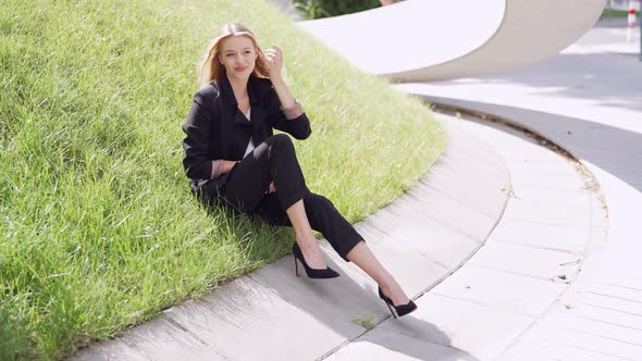 Positive Businesswoman Sitting on Grass