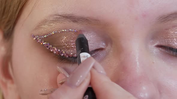 A Professional Makeup Artist Applies Special Rhinestones to the Eyes and Eyelids of a Young