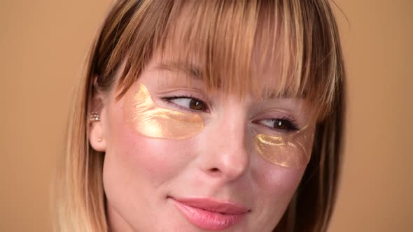 Beautiful Smiling Woman with Short Hair in Gold Eye Patches Looking in Camera and Smiling Over