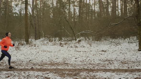 Girl running in snowy winter park training for marathon. Trail run concept. Weight loss concept