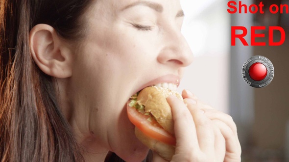 Beautiful Woman Eating Cheeseburger With Delight And Indulging With The Taste