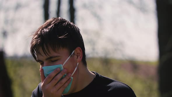 Close Up of Young Caucasian Man Taking on Medical Mask Outdoor. Sick Guy Wearing Protection During