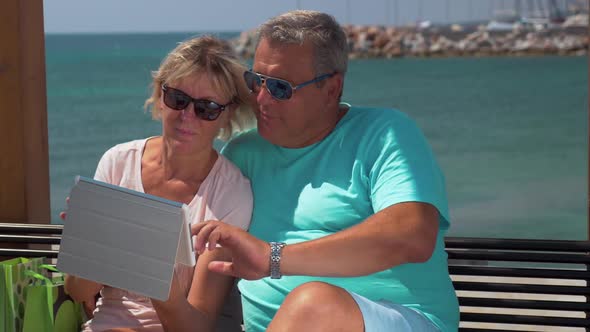 Senior Couple Using Touch Pad on Waterfront