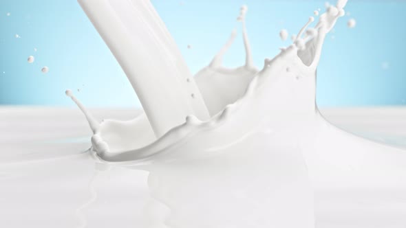 Super Slow Motion Shot of Pouring and Splashing Fresh Milk on Blue Background at 1000 Fps alt