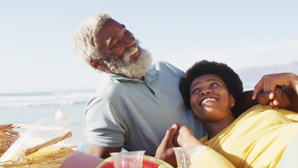 Happy african american couple having picnic on sunny beach