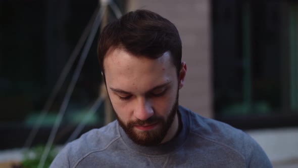 Close-up face of bearded young man wearing medical face mask, looking away on empty city street