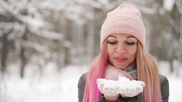 Slow Motion, a Woman in a Jacket Hat and Scarf in the Winter in the Forest Holding Snow in Her Hands