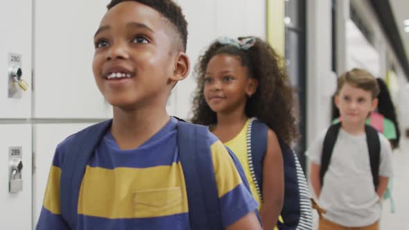 Video of happy diverse pupils standing in row and smiling before entering classroom