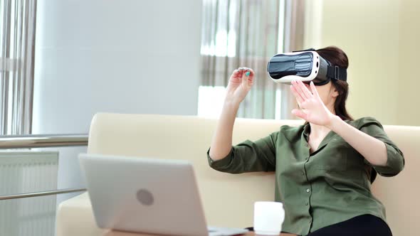 Smiling Female Gesticulating in Modern Virtual Reality Glasses in Front of Computer Pc