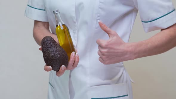 Nutritionist Doctor Holding Organic Avocado Fruit and Bottle of Oil