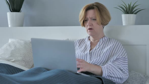 Reaction of Loss By Sad Senior Woman Using Laptop in Bed