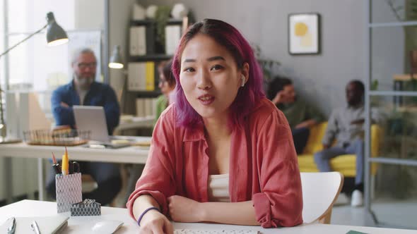 Cheerful Asian Woman Talking on Camera on Video Call in Office