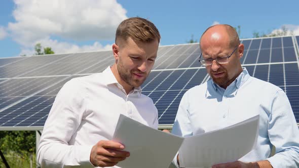 Two Workers Check the Installed Solar Panels alt
