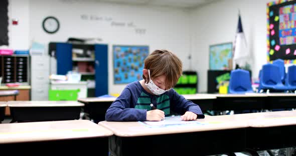 As students return to school during the COVID 19 Coronavirus pandemic a young boy wearing a mask com