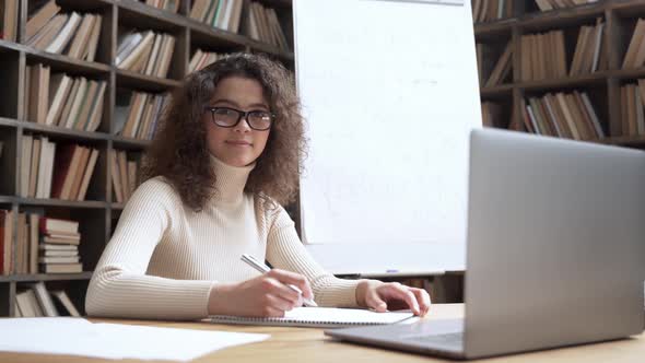 Smiling Hispanic School Math Teacher Looking at Camera in Classroom with Laptop